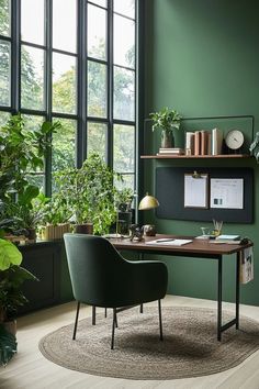 an office with green walls and plants in the corner, along with a rug on the floor