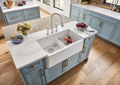 a kitchen with blue cabinets and white counter tops, an island style sink is in the center