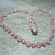 Graduated beads of alternative Rose pink Quartz beads and pink Glass Cat's Eye beads feature in this soft pink necklace. At each end of the necklace the Rose Quartz beads are 6mm with 4mm Cat's Eye beads while in the middle we have 8mm Rose Quartz beads and 6mm Glass Cat's Eye beads. The necklace has a Platinum plated Brass magnetic clasp and comes with free matching earrings with Silver plated Stainless Steel earwires. Necklace and Earrings come contained within an organza bag. Rose Quartz has a very soothing, comforting energy and can help heal pain, grief and heartbreak. Its energy is accepting, nurturing, generous and kind. It comforts when you feel broken or weary helping you accept and nurture yourself. A crystal of unconditional love. It carries an energy of compassion, comfort, hea Elegant Pink Beaded Necklaces With 8mm Beads, Elegant Pink Beaded Necklace With 8mm Beads, Elegant Pink Necklaces With 8mm Beads, Pink Rose Quartz Beaded Necklaces As Gifts, Pink Single Strand Round Beads Necklace, Pink Single Strand Necklace With Round Beads, Pink Necklaces With 8mm Beads, Handmade Rose Quartz Bead Necklace, Pink 8mm Beaded Necklace