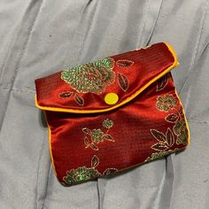 a red and gold purse sitting on top of a bed