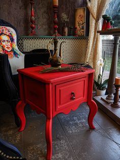 a red table with candles on it in front of a mirror and other items around the room