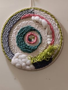 a circular wall hanging made out of woven material with various colors and designs on it