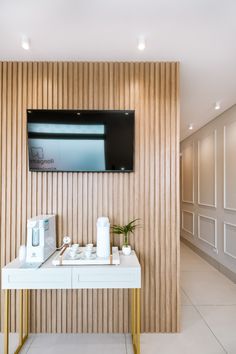 there is a tv mounted on the wall above a table with two cups and coffee mugs