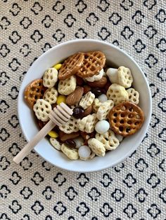 a bowl filled with cereal and pretzels on top of a patterned table cloth