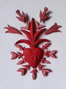 a red heart and some leaves on a white surface