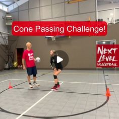 two men are playing volleyball in an indoor court with cones on the floor and one man is holding a ball