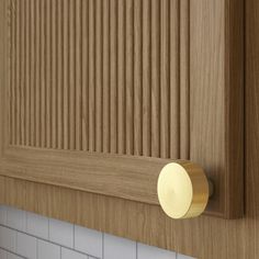 a close up of a door handle on a wooden cabinet with white tile and wood grained walls