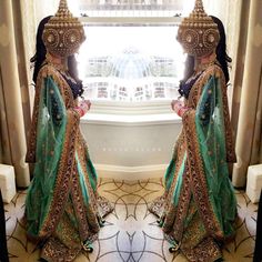 a woman in a green and gold bridal gown standing next to a large window