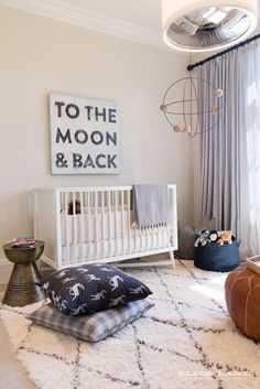 a baby's room with a white crib, black and white pillows, and a large poster on the wall