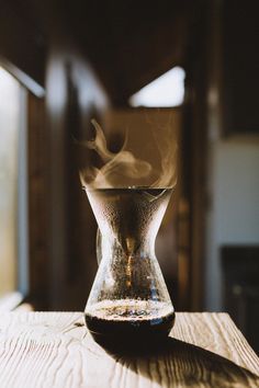 a glass vase filled with liquid on top of a wooden table