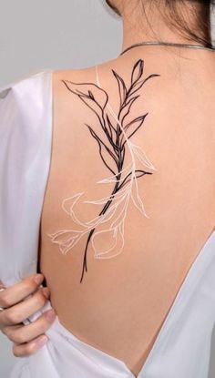 the back of a woman's shoulder with flowers on it and leaves drawn in white ink