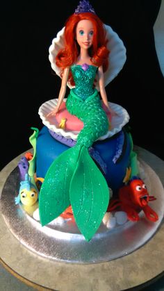 there is a little mermaid on top of the cake