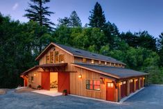 a garage with an attached carport in the middle of a driveway surrounded by trees