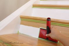 someone is painting the stairs with red and green paint on it, while another hand holds a roller