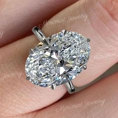 a close up of a person's hand with a diamond ring on their finger