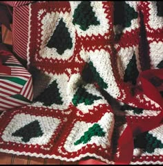 a crocheted christmas blanket with holly leaves on it and red ribbon around the edges