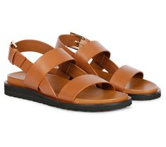 Step into summer with these leather sandals, a perfect fusion of craftsmanship and contemporary style. They feature chic front straps and an adjustable ankle strap, offering both a modern look and a comfortable fit. The padded leather footbed ensures all-day comfort, making them your ideal choice for any occasion, from casual strolls to professional gatherings. From Saint G. Leather Sport Sandals With Strap For Summer, Leather Sport Sandals With Strap For Vacation, Leather Strap Sport Sandals For Summer, Leather Strap Sport Sandals For Vacation, Leather Open Toe Sport Sandals With Strap, Leather Double Strap T-strap Sandals, Chic Leather Strap Sandals, Modern Double Strap Sandals, Summer Double Strap Sandals With Leather Sole