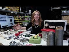 a woman sitting in front of a computer screen surrounded by sewing supplies and other items