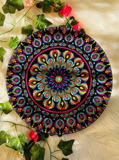 a colorful circular design on a white fur with flowers and leaves around the edges is featured in this image