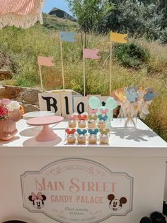 an ice cream stand with mickey and minnie mouse cupcakes on it's table