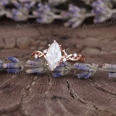 an engagement ring with a pear shaped diamond surrounded by lavenders on a piece of wood