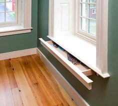 an empty window sill in the corner of a room with wood floors and green walls