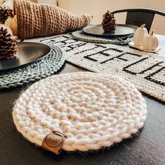 knitted placemats and plates on a table with pine cones in the background