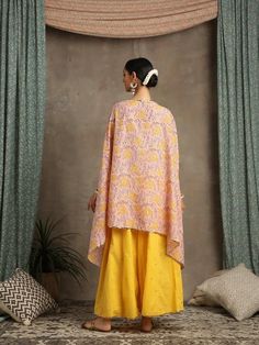 Set of 2 consists of cape and palazzo. Bouquet of floral yellows hand-printed on a pastel peach base. A quintessential summer cape/kaftan set perfect for the upcoming festivities. Comes with dainty gota highlights and handmade button detailing. Combined with kali palazzo in yellow with handwork zari and gota detailing. Colour - Peach Material - Cotton and Kota Doria Occasion - Festive Wear Fit - Relaxed and Flowy Pattern - Printed Care - Dry Clean only Estimated Delivery 15-20 days Heer- These a