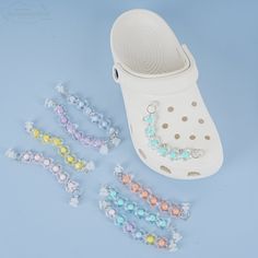 a pair of white shoes with beaded bracelets next to them on a blue surface