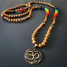 The Chakra Colors Yoga Mala Beaded Necklace is a spiritual and meaningful piece of handmade jewelry that combines natural elements and powerful symbolism. This unique necklace is commonly used in meditation and yoga practices to enhance the spiritual experience and promote a sense of balance and harmony.The handmade necklace is made with natural sandalwood beads, which are known for their calming and soothing properties. Sandalwood has been used for centuries in various spiritual practices to he Spiritual Wooden Beads Jewelry For Meditation, Spiritual Wooden Beads Mala For Festival, Holistic Necklaces With 8mm Beads For Rituals, Spiritual Wooden Beads Jewelry For Healing, Spiritual Necklaces With 108 Beads For Rituals, Healing 108 Beads Jewelry For Festivals, Spiritual Round Beads Jewelry For Festivals, 108 Beads Jewelry For Healing And Festivals, Bohemian Mala With 108 Beads For Festivals