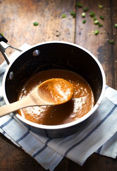 a wooden spoon in a pot filled with sauce on top of a blue and white towel