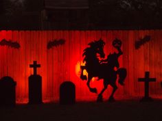 the shadow of a horse and rider on a fence is projected in front of tombstones