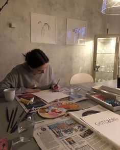 a woman sitting at a table with papers and pens