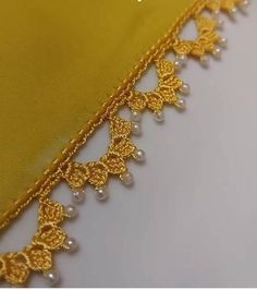 an image of a yellow fabric with gold trimmings and pearls on the edge