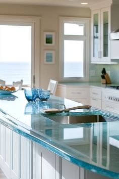 a kitchen with an island and blue counter tops in front of the window overlooking the ocean