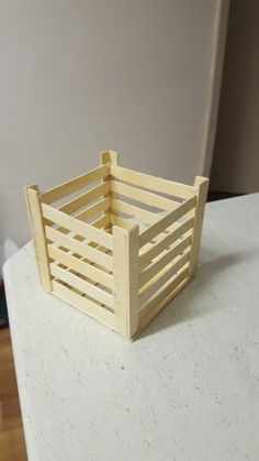 a small wooden crate sitting on top of a counter next to a white wall and hardwood floor