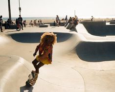 a person riding a skateboard at a skate park with other people on the beach in the background