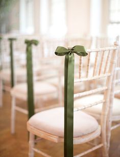 the chairs are decorated with green ribbons and bows for guests to sit down at their wedding ceremony