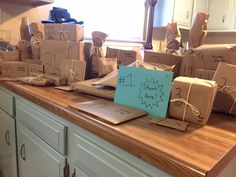 many wrapped presents sit on top of a kitchen counter with a note pinned to it