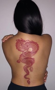 the back of a woman's body with a red dragon tattoo on her shoulder