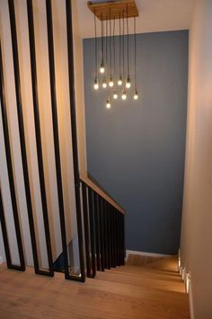 the light fixture is hanging from the ceiling above the stairs in this house, which has striped walls and wood flooring