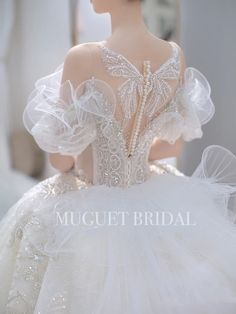 the back of a white wedding dress with ruffles and beading on it