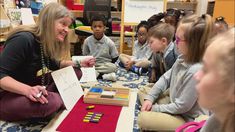 a woman sitting on the floor in front of children with blocks and crayons