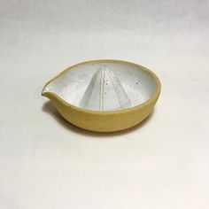 a yellow and white ceramic dish on a white surface