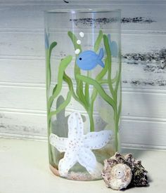 a glass vase with seaweed, starfish and other marine life in it sitting on a table