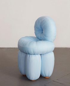 a large blue chair sitting on top of a cement floor next to a white wall