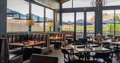 a restaurant with tables, chairs and windows looking out onto the mountains in the distance