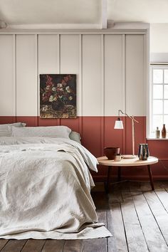 a bedroom with white walls and wood flooring is pictured in this image, the bed has two nightstands on each side