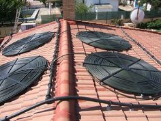 several round metal objects sitting on top of a red brick roof in front of a building