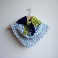 a crocheted scarf hanging from a hook on a white wall next to a wooden hanger